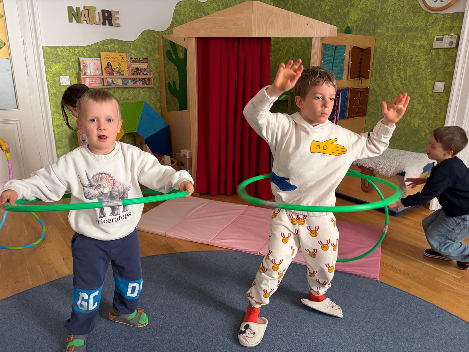 Kinder bewegen sich mit grünen Reifen im Gruppenraum
