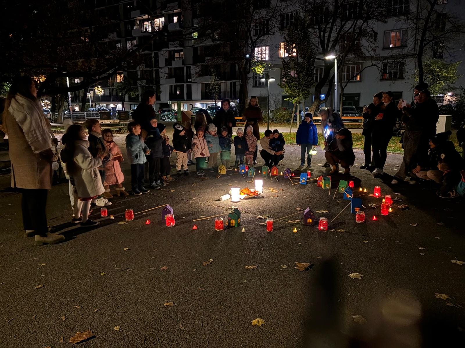 Kinder und Erwachsene stehen abends um einen Kreis aus bunten Laternen