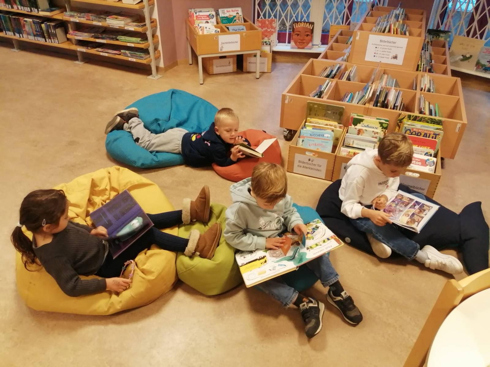 Kinder schauen sich Bücher auf Sitzsäcken in einer Bibliothek an