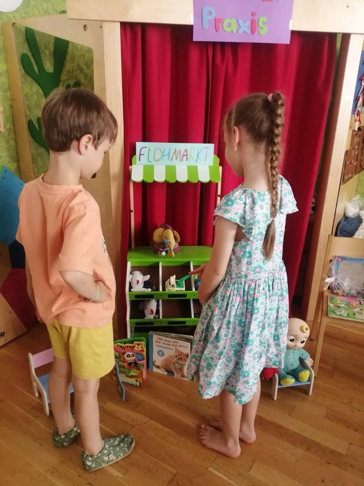 Zwei Kinder spielen gemeinsam an einem kleinen Marktstand