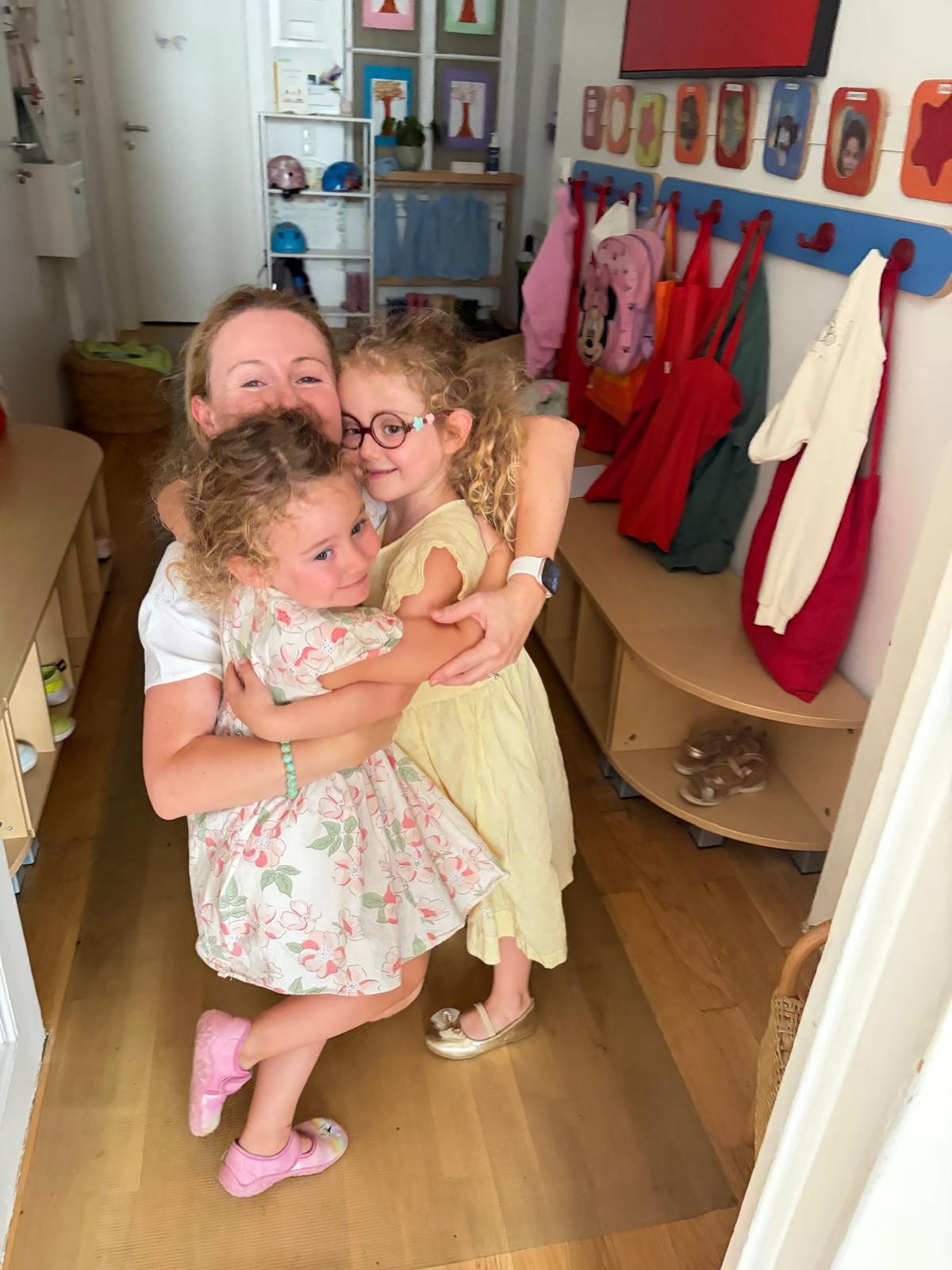 Eine Erwachsene und zwei Kinder umarmen sich in der Garderobe